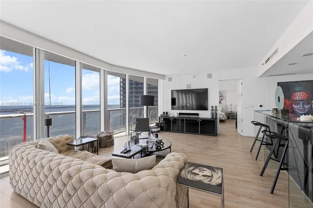 a living room with furniture a flat screen tv and a large window