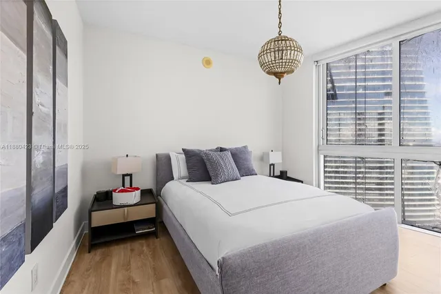 a bedroom with a bed a chandelier and a window