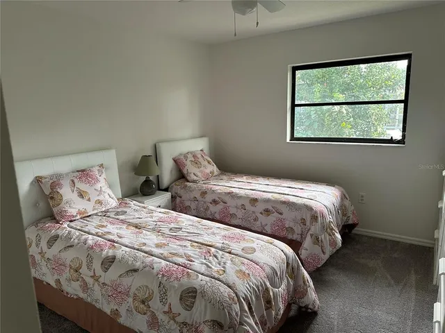 a bedroom with two beds and next to a window