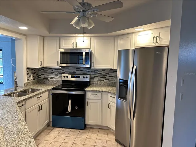 a kitchen with stainless steel appliances granite countertop a refrigerator a stove a sink and a microwave