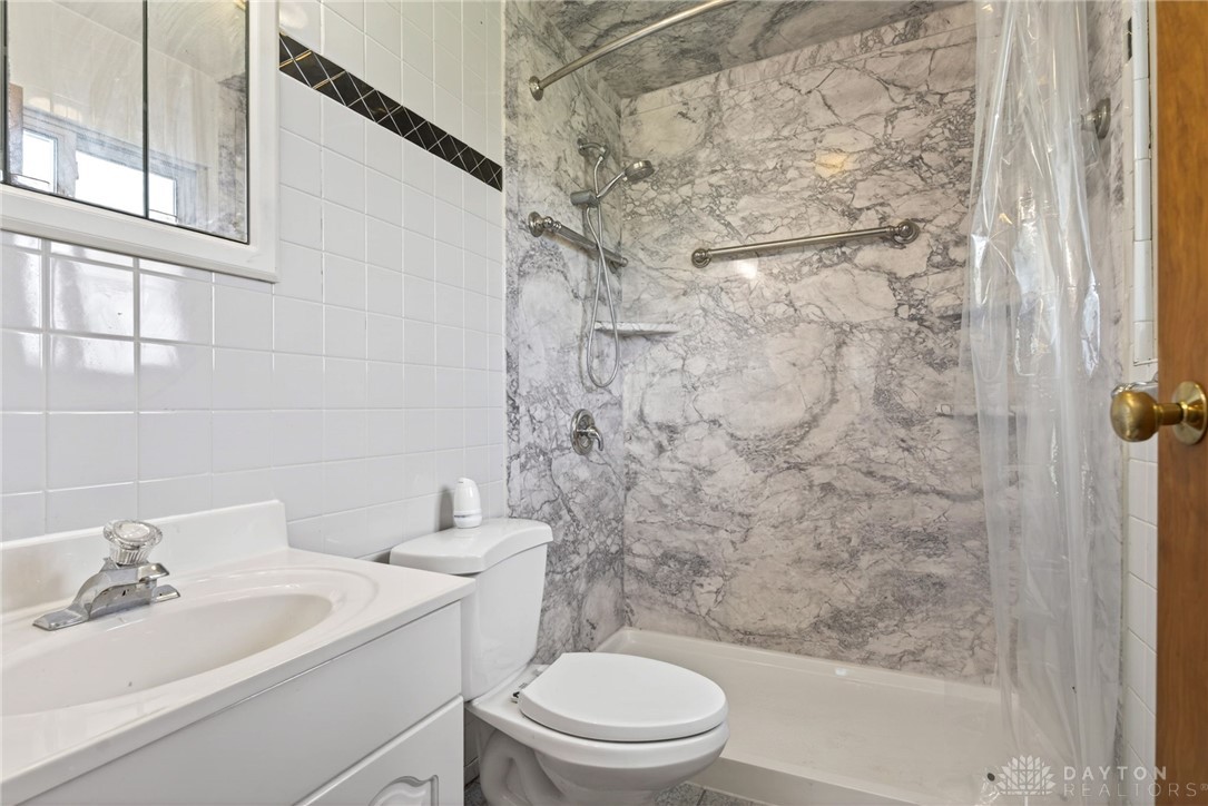1005 Free Road New Carlisle, OH 45344 - Photo 23 of 43 This bathroom features pristine white tiling complemented by elegant marble-patterned shower walls.