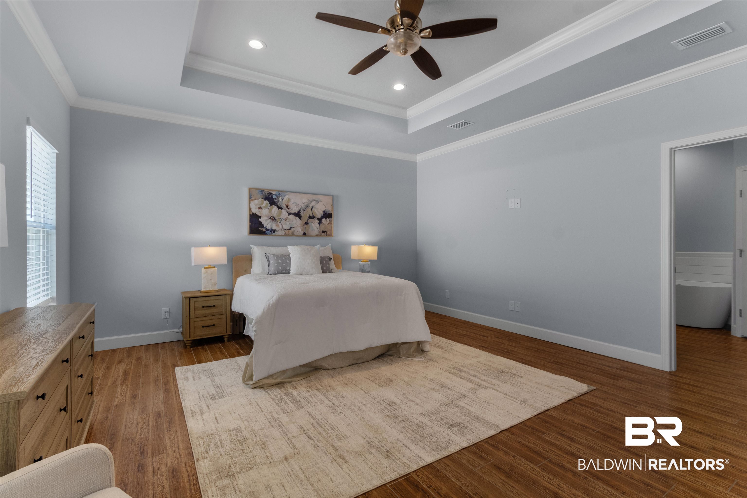 927 Periwinkle Lane Foley, AL 36535 - Photo 7 of 26 Spacious bedroom featuring wood-finish flooring, a tray ceiling with recessed lighting and a ceiling fan, and crown molding