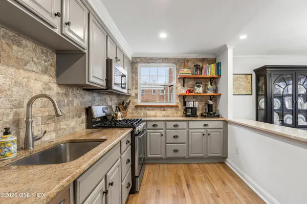 a kitchen with stainless steel appliances granite countertop a sink a stove and cabinets