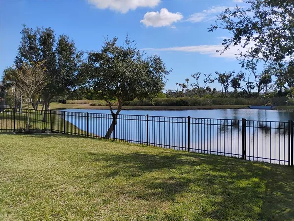 a view of a lake with a big yard and potted plants