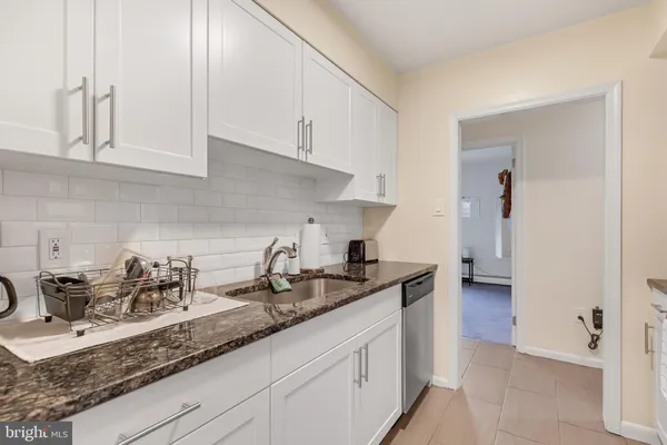a kitchen with granite countertop white cabinets and a sink