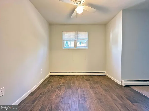 an empty room with wooden floor chandelier fan and windows