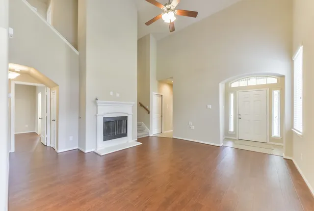 an empty room with wooden floor fireplace and windows