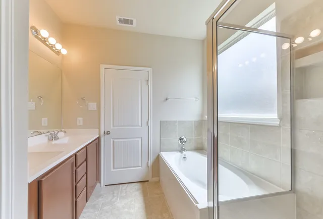 a bathroom with a tub sink shower and mirror