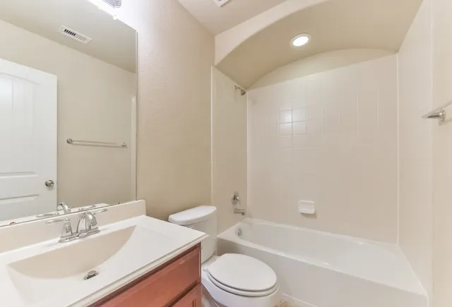 a bathroom with a bathtub shower sink vanity mirror and toilet