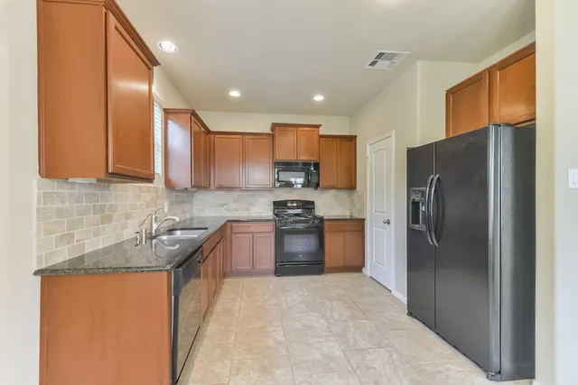 a kitchen with stainless steel appliances granite countertop a refrigerator sink and stove