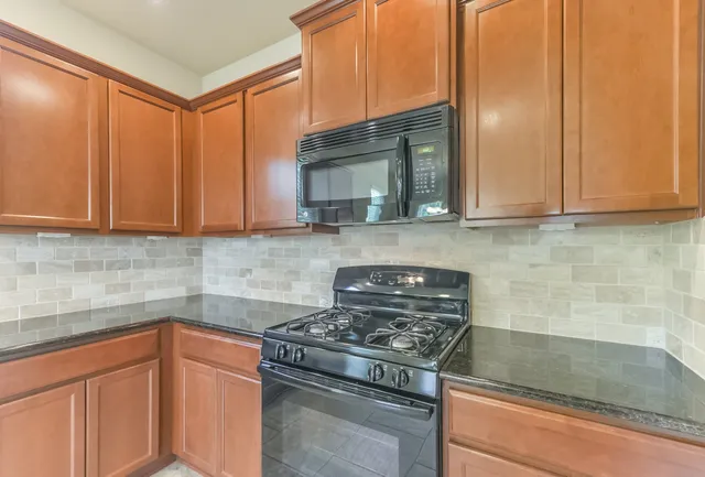 a kitchen with stainless steel appliances granite countertop white cabinets and a stove top oven