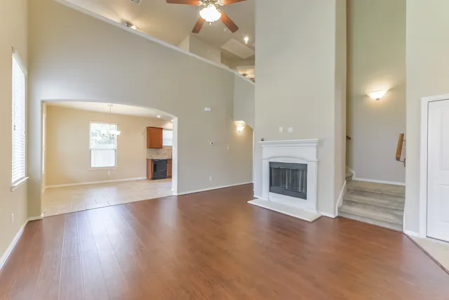 an empty room with wooden floor fireplace and windows