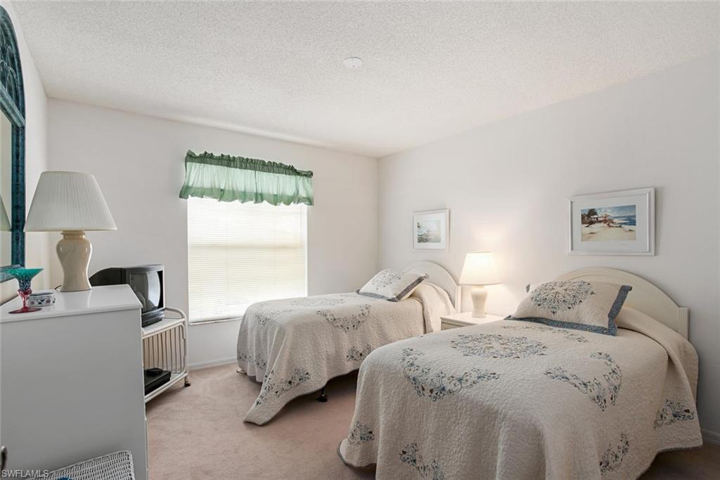 741 Landover Circle, Unit 203 Naples, FL 34104 - Photo 12 of 21 a bedroom with two beds and a window