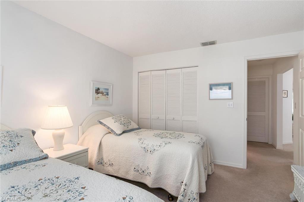 741 Landover Circle, Unit 203 Naples, FL 34104 - Photo 13 of 21 a bedroom with a bed and a lamp