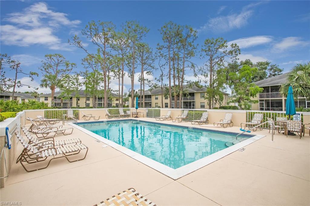 741 Landover Circle, Unit 203 Naples, FL 34104 - Photo 17 of 21 a view of a swimming pool with a patio and a yard