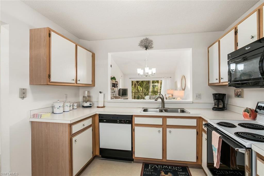 741 Landover Circle, Unit 203 Naples, FL 34104 - Photo 4 of 21 a kitchen with stainless steel appliances a sink stove and microwave