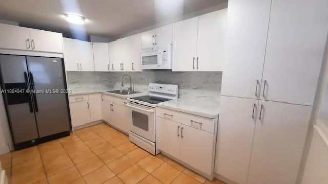 a kitchen with white cabinets and white appliances