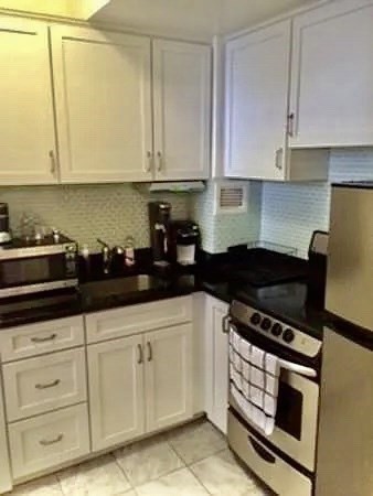 21 Beacon Street, Unit 6D Boston, MA 02108 - Photo 6 of 21 a kitchen with granite countertop white cabinets and black appliances