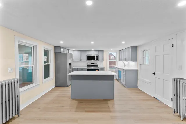 a living room with stainless steel appliances kitchen island granite countertop a stove and a refrigerator