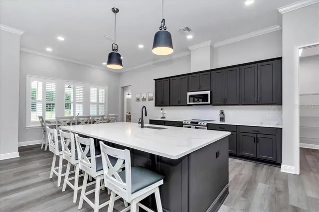 a kitchen with stainless steel appliances kitchen island granite countertop a stove a sink a microwave and wooden cabinets