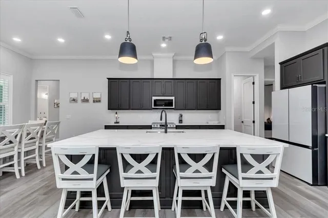 a kitchen with stainless steel appliances a dining table chairs refrigerator and microwave