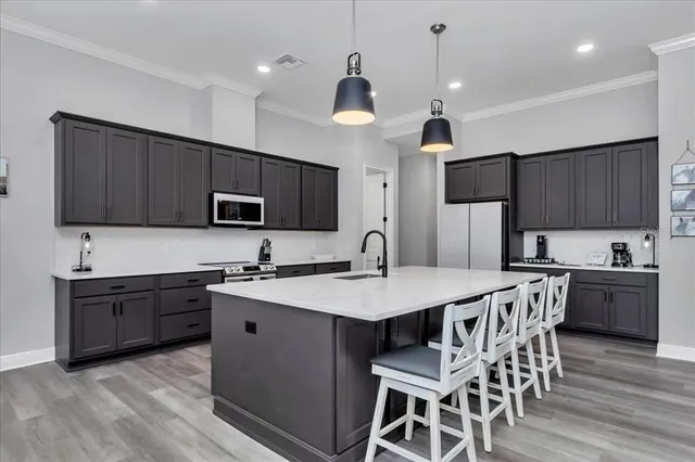 a kitchen with granite countertop a sink stove a microwave oven a refrigerator with wooden floor and cabinets