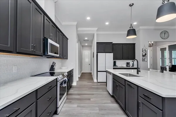 a kitchen with stainless steel appliances a sink dishwasher a stove top oven a refrigerator with wooden cabinets and floor