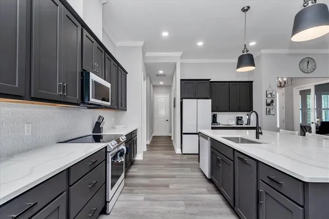 a kitchen with stainless steel appliances a sink dishwasher a stove top oven a refrigerator with wooden cabinets and floor