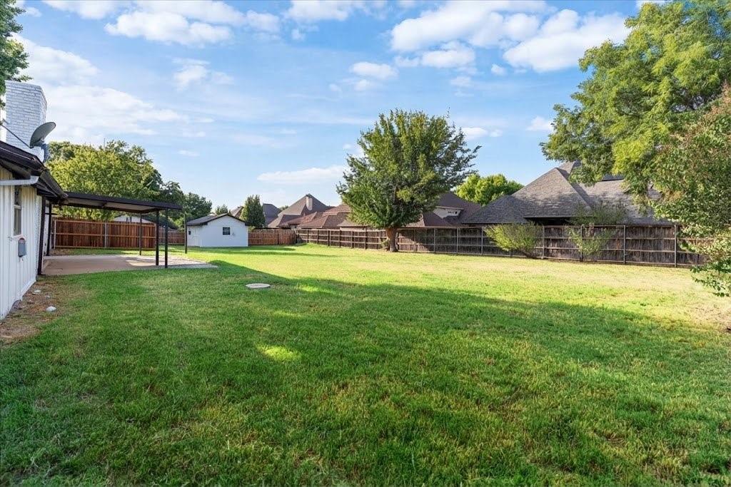 3509 West Sublett Road Arlington, TX 76017 - Photo 35 of 39 Expansive green lawn with a covered concrete patio, privacy fencing, and a detached storage shed