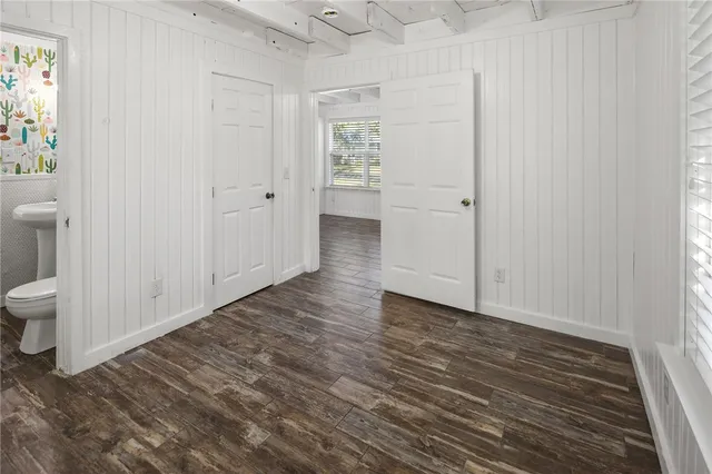 a view of an empty room and bathroom with wooden floor