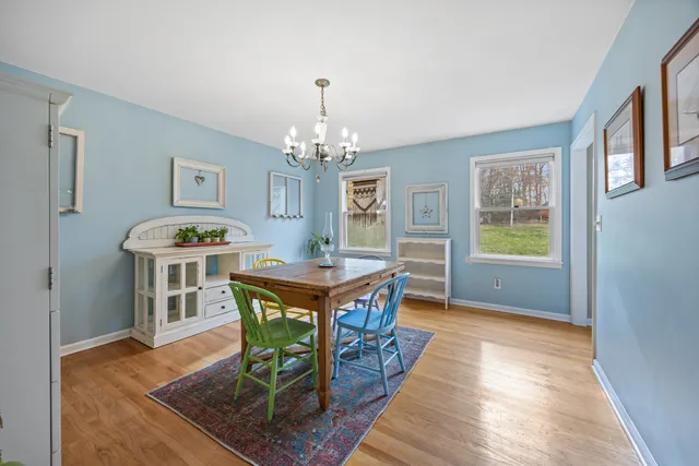 a dining room with chandelier and wooden floor