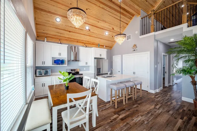 a dining room with wooden floor a chandelier a wooden table and chairs