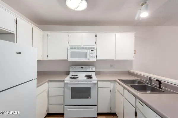 a kitchen with white cabinets sink and white appliances