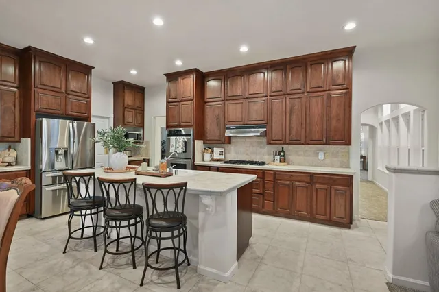 a kitchen with stainless steel appliances granite countertop a table chairs sink refrigerator and microwave