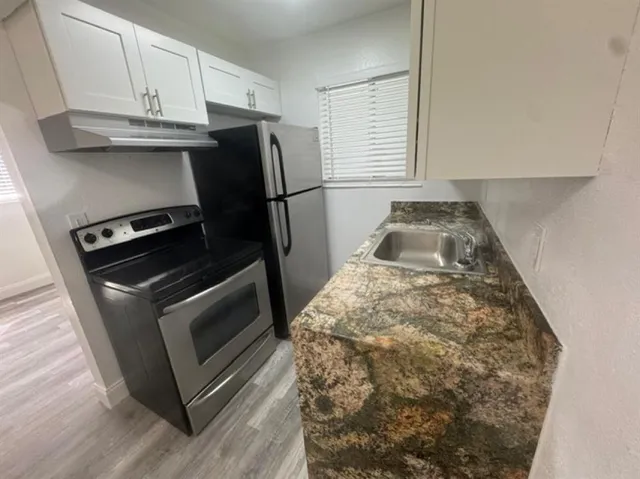 a kitchen with granite countertop white cabinets and stainless steel appliances