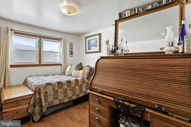 a bedroom with a bed and a dresser next to a window