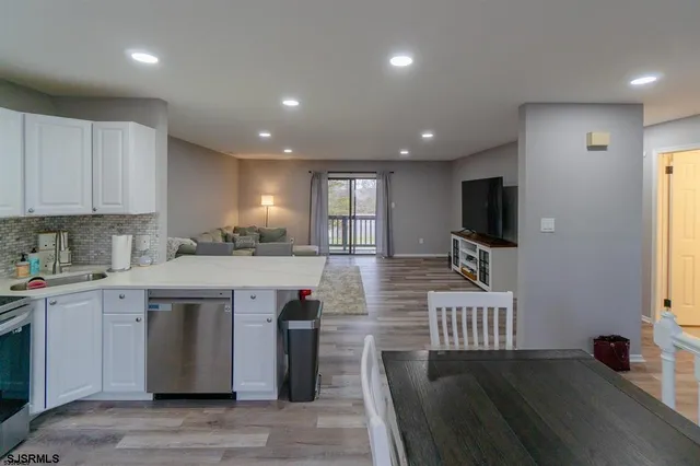 a kitchen with stainless steel appliances granite countertop a stove a sink dishwasher and a refrigerator with wooden floor