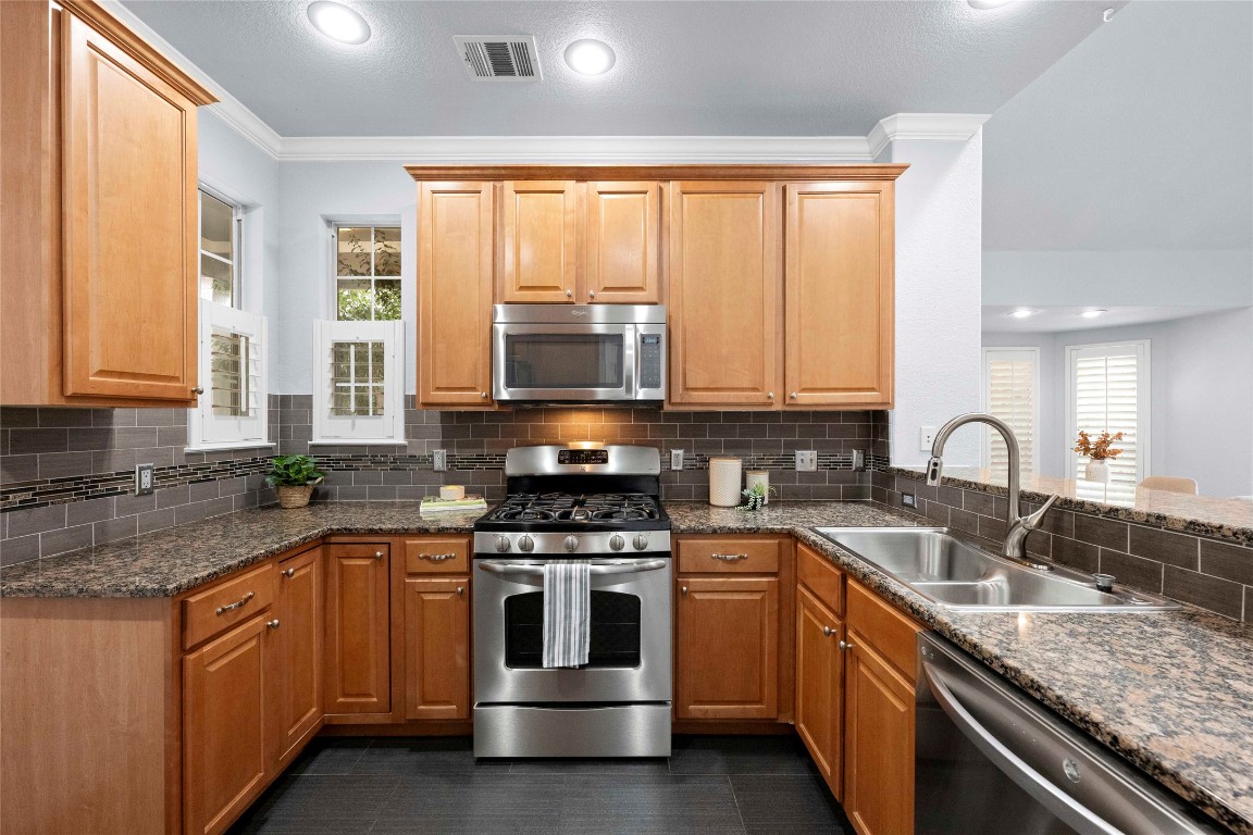 6704 Menchaca Road, Unit 29 Austin, TX 78745 - Photo 10 of 34 a kitchen with stainless steel appliances granite countertop a stove sink and cabinets