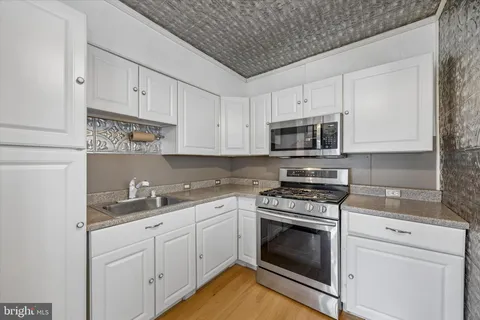 a kitchen with white cabinets stainless steel appliances and sink