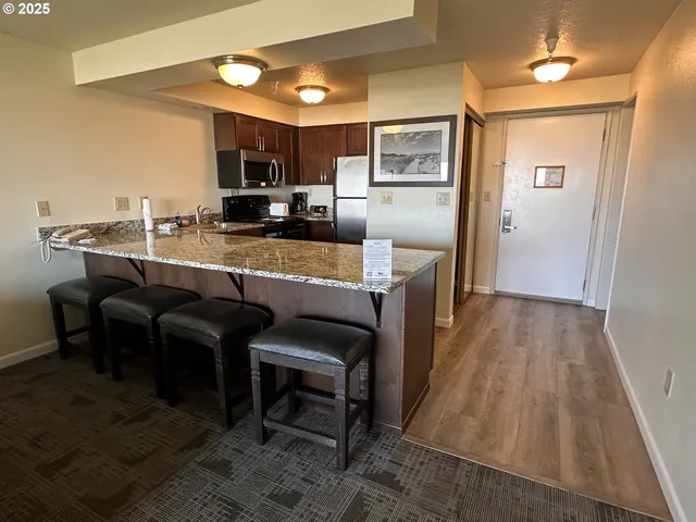 a kitchen with kitchen island granite countertop wooden cabinets and stainless steel appliances