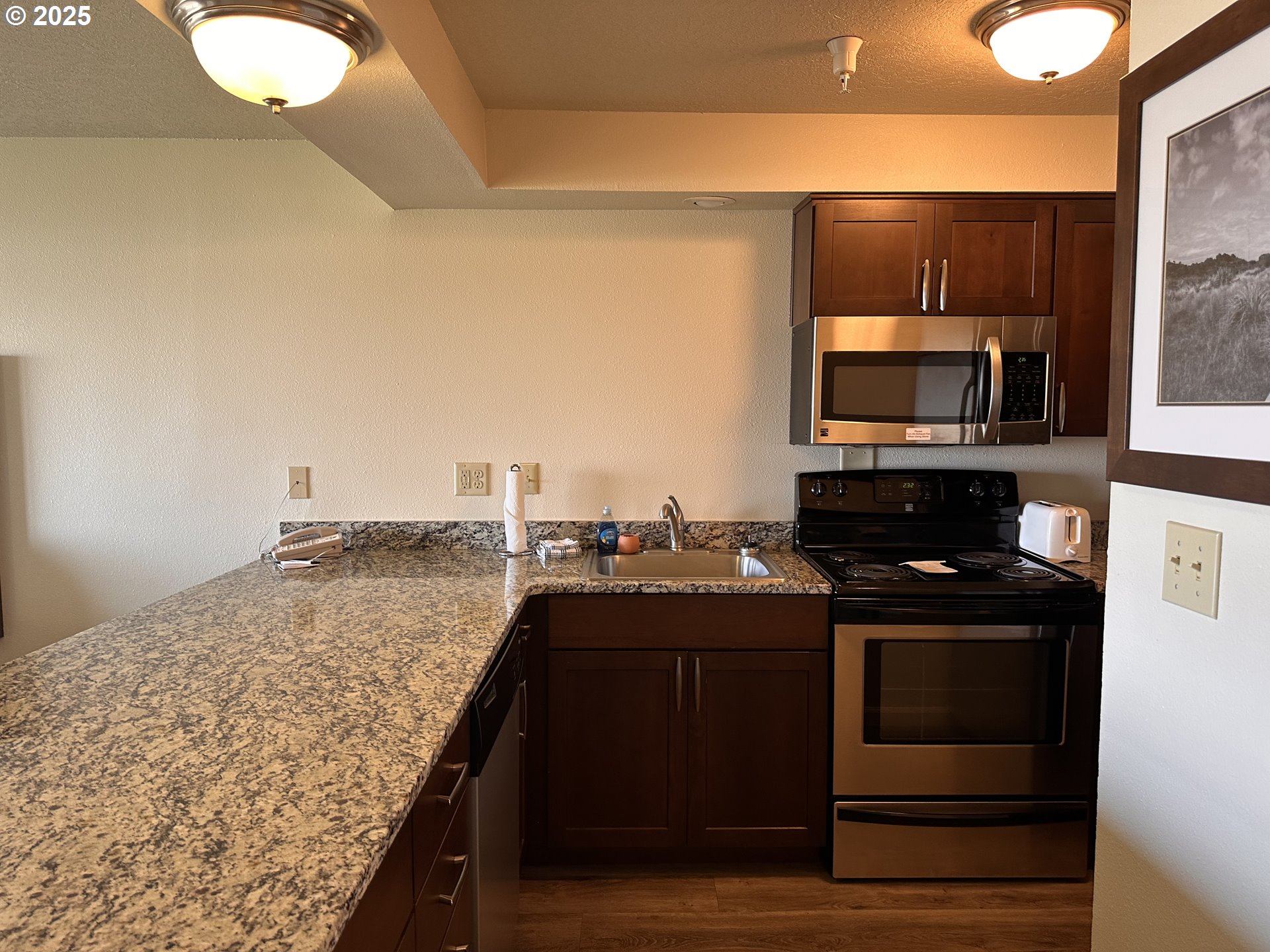 88416 1st Avenue, Unit 303 Florence, OR 97439 - Photo 6 of 21 a kitchen with kitchen island granite countertop a stove top oven microwave and cabinets