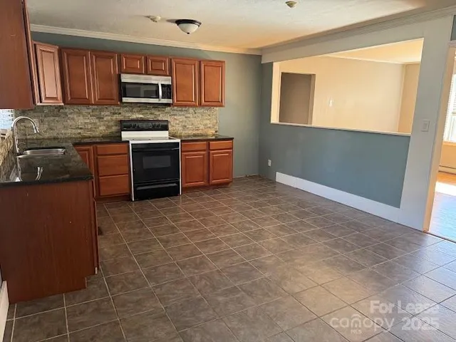 a kitchen with stainless steel appliances granite countertop a stove a sink and a microwave