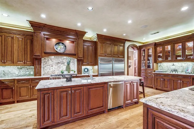 a large kitchen with a large counter top a sink stainless steel appliances and cabinets