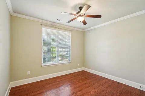 an empty room with wooden floor closet and windows