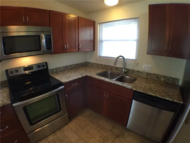 a kitchen with granite countertop a stove microwave and sink