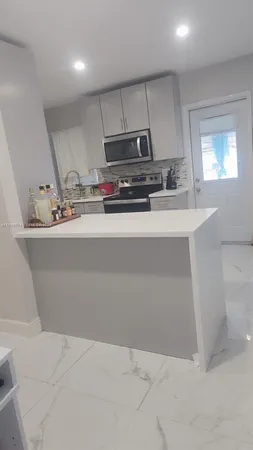 a view of kitchen with stainless steel appliances granite countertop a sink a stove a refrigerator cabinets and a dining table