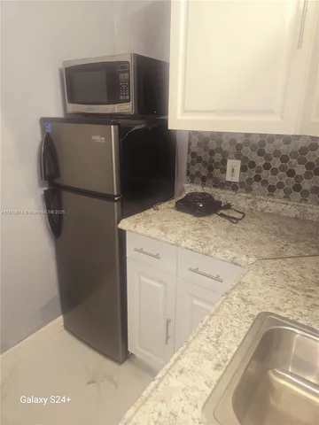 a bathroom with a granite countertop sink and washing machine