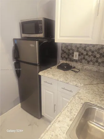 a bathroom with a granite countertop sink and washing machine