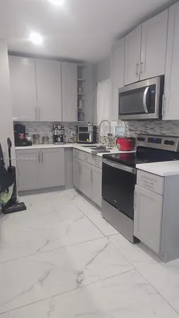 a kitchen with granite countertop a sink and white cabinets