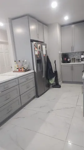a view of a kitchen with refrigerator and white cabinets